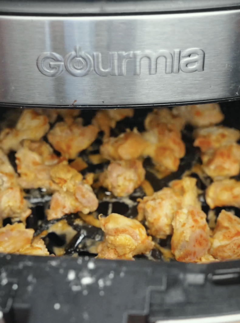 Chicken thighs cooking inside an air fryer until golden brown and crispy. Air frying creates crunchy chicken pieces with less oil while keeping the inside tender and juicy.