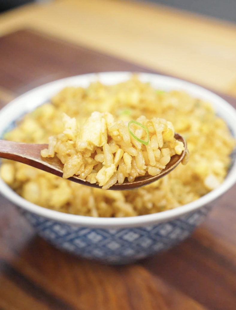 Spoonful of homemade Egg Fried Rice lifted above a bowl, showing fluffy scrambled eggs, seasoned rice, and sliced scallions. This quick and easy fried rice recipe delivers classic takeout flavor with simple pantry ingredients.