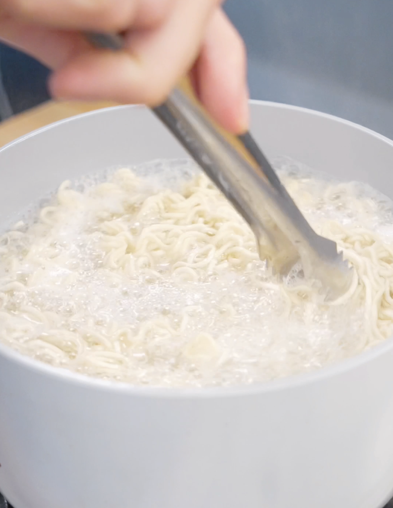 Noodles boiling in a pot of water until just before al dente for this quick and easy Creamy Chili Oil Noodles Recipe. Reserving the noodle water helps create a silky sauce later.