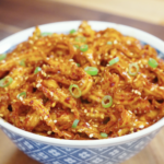 Bowl of glossy Spicy Garlic Noodles Recipe topped with sesame seeds and scallions for an easy and flavorful weeknight noodle dinner.