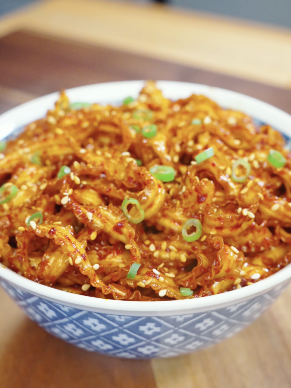 Bowl of glossy Spicy Garlic Noodles Recipe topped with sesame seeds and scallions for an easy and flavorful weeknight noodle dinner.