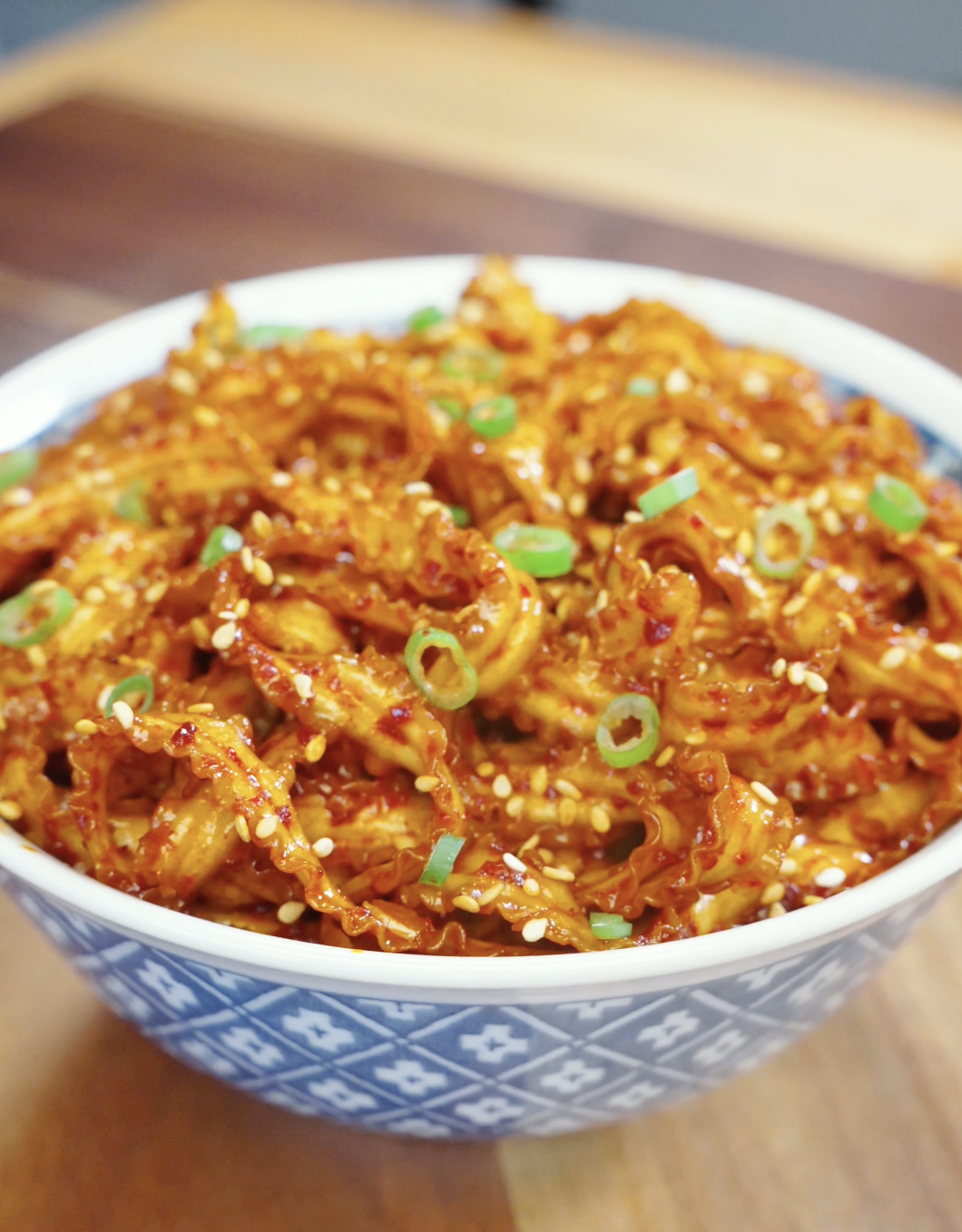 Bowl of glossy Spicy Garlic Noodles Recipe topped with sesame seeds and scallions for an easy and flavorful weeknight noodle dinner.