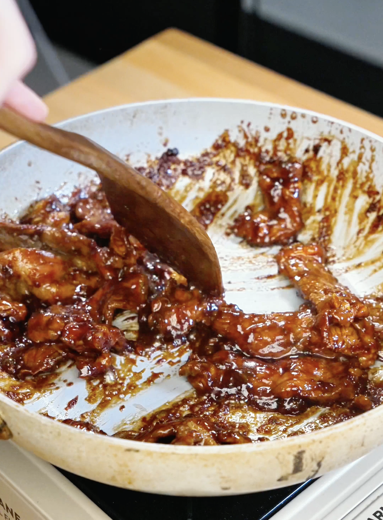 Thinly sliced lemongrass beef caramelizing in a pan with a glossy soy and fish sauce glaze as the sauce thickens around the tender beef strips in this easy Lemongrass Beef Recipe.