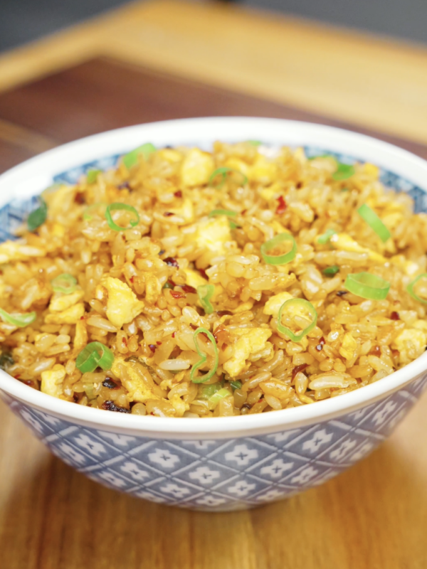 Bowl of Chili Oil Butter Fried Rice topped with scallions featuring fluffy eggs, glossy rice grains, garlic, and spicy chili oil for an easy comfort food dinner recipe.