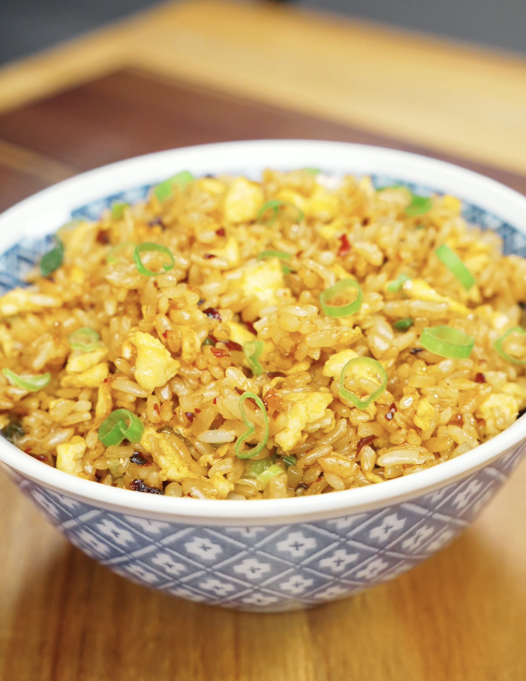 Bowl of Chili Oil Butter Fried Rice topped with scallions featuring fluffy eggs, glossy rice grains, garlic, and spicy chili oil for an easy comfort food dinner recipe.