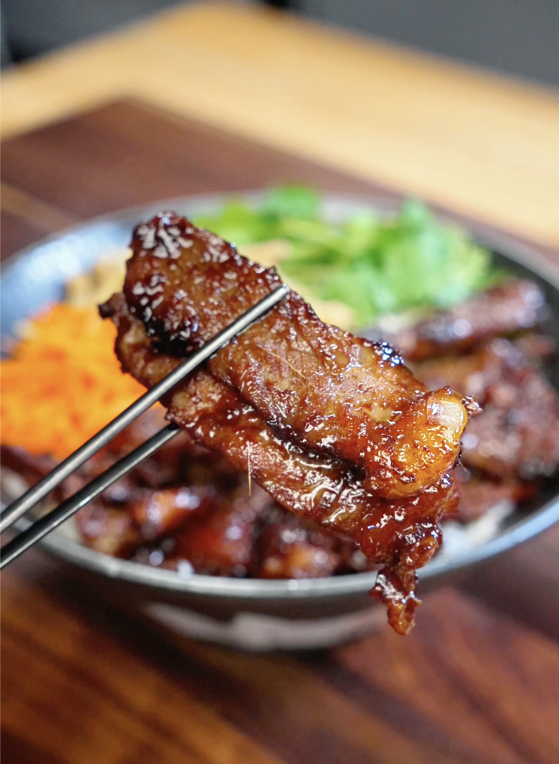 Close-up of caramelized lemongrass beef held with chopsticks showing the glossy savory glaze and tender texture in this quick and easy Lemongrass Beef Recipe.