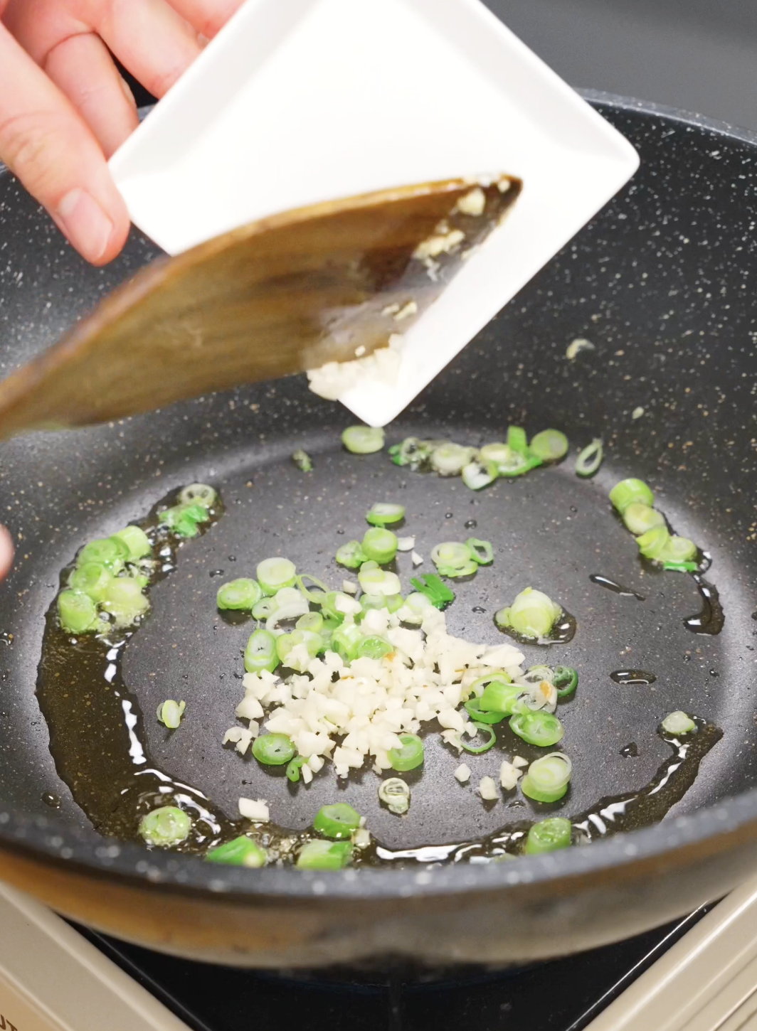 Minced garlic and sliced scallion whites saut&eacute;ing in oil in a skillet to build flavor for homemade Chili Oil Butter Fried Rice Recipe.