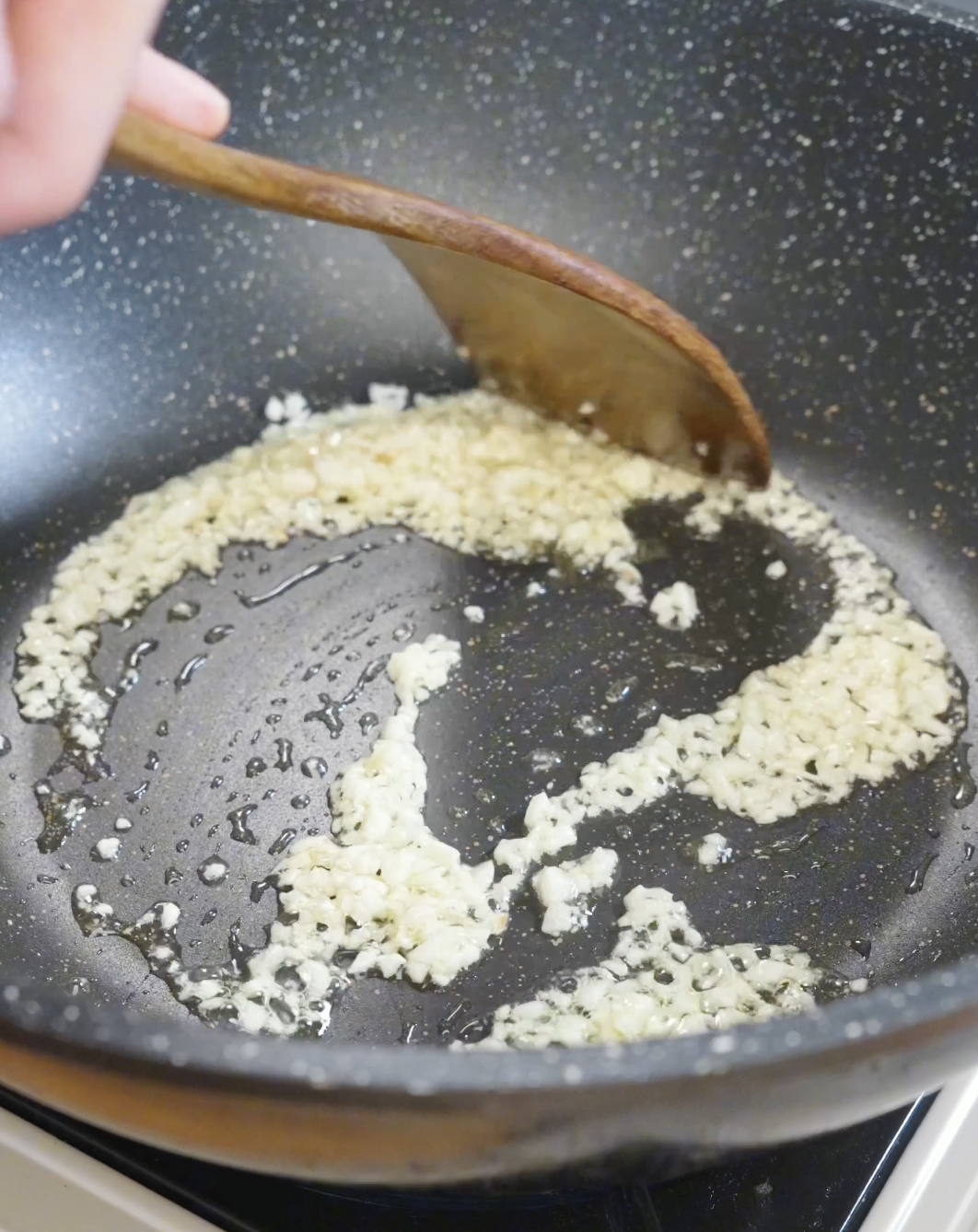 Fresh minced garlic saut&eacute;ing in oil in a skillet to create the aromatic base for homemade Spicy Garlic Noodles Recipe.