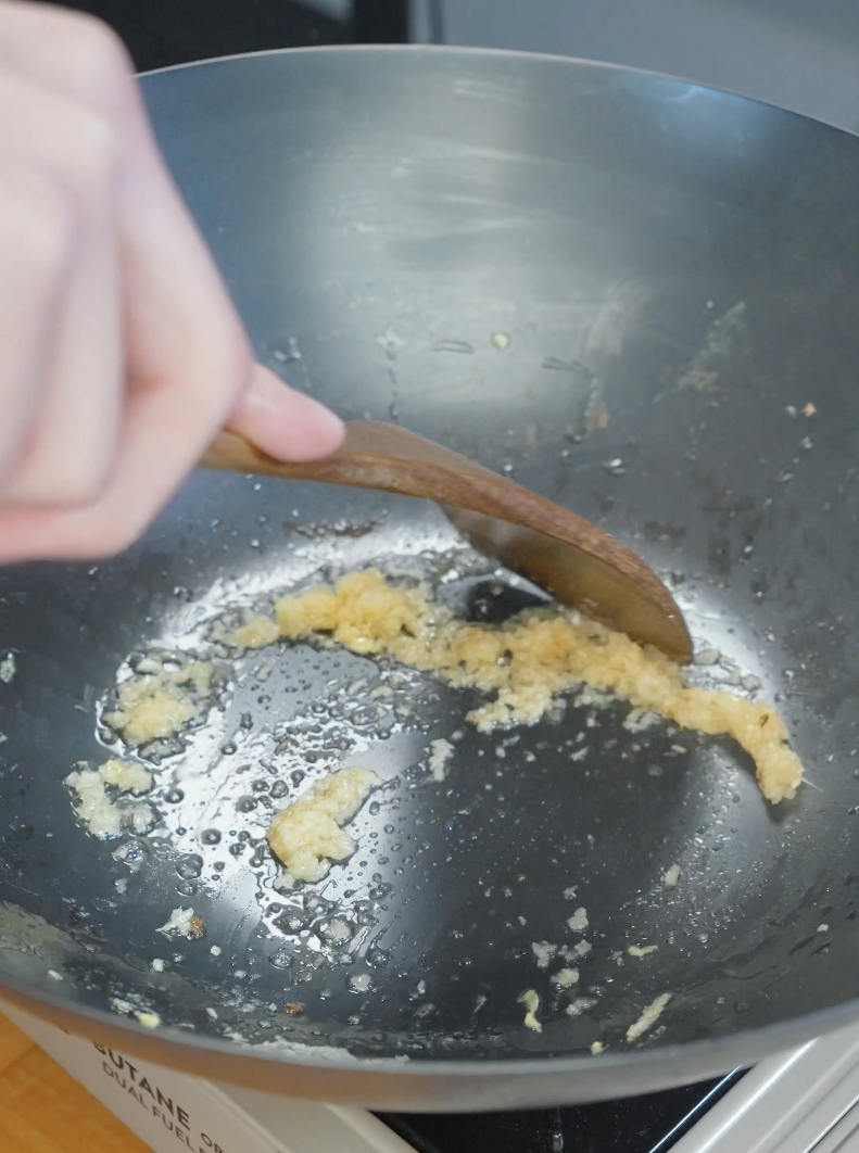 Minced ginger saut&eacute;ing in oil inside a wok to build flavor for the Japanese Ground Beef Egg Bowl Recipe.