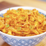 Bowl of Gochujang Butter Noodles garnished with sesame seeds and sliced scallions. The noodles are coated in a glossy, spicy, buttery sauce that delivers the perfect balance of heat, richness, and savory flavor.
