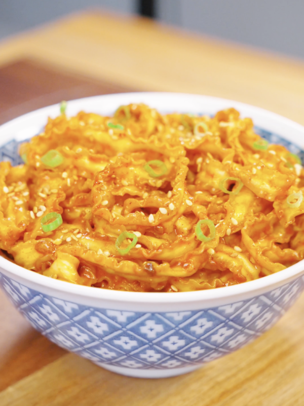 Bowl of Gochujang Butter Noodles garnished with sesame seeds and sliced scallions. The noodles are coated in a glossy, spicy, buttery sauce that delivers the perfect balance of heat, richness, and savory flavor.