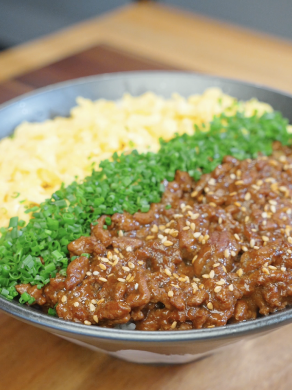 Japanese Ground Beef Egg Bowl Recipe served with fluffy scrambled eggs, chopped chives, sesame seeds, and savory glazed ground beef over rice.