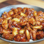 Bowl of glossy chicken thighs and softened whole garlic cloves coated in a thick savory sauce in the Whole Garlic Chicken Stir Fry Recipe.