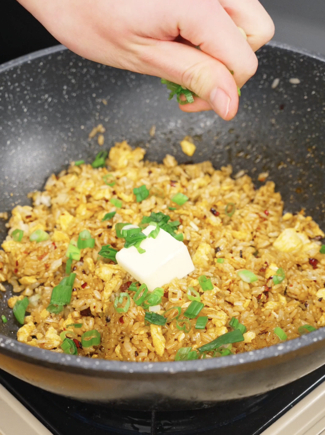 Cube of butter and fresh scallions added to spicy fried rice in a skillet to create rich buttery flavor in this Chili Oil Butter Fried Rice Recipe.