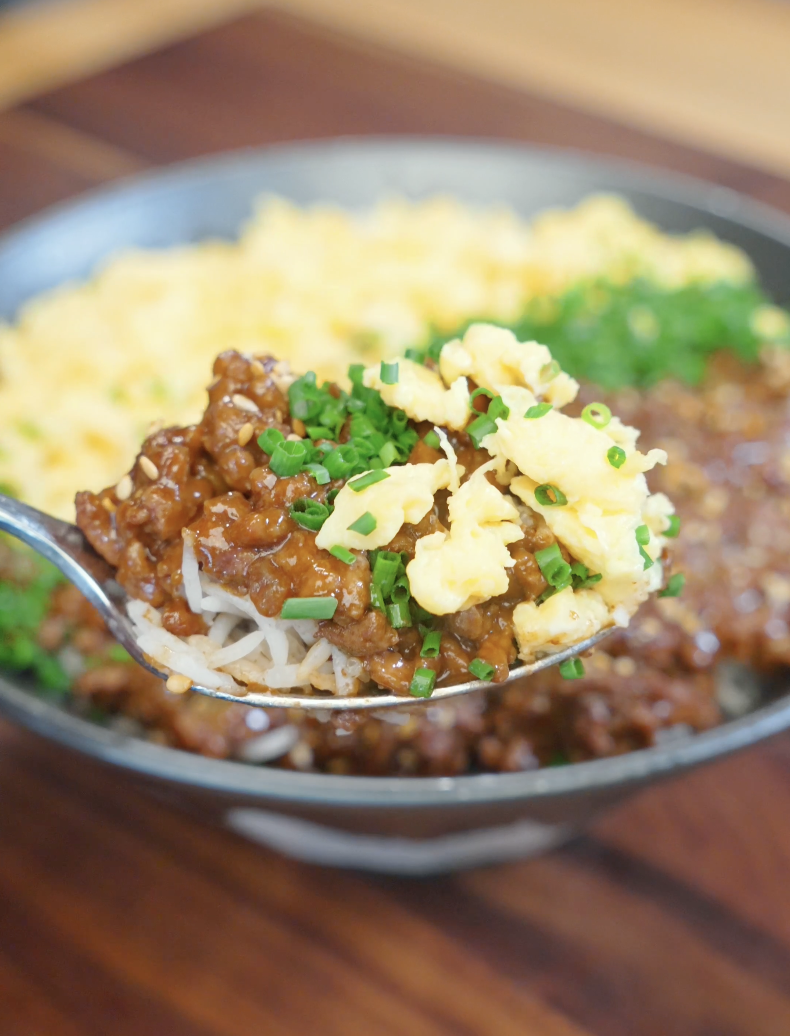Spoon lifting savory soy-glazed ground beef over rice from the Japanese Ground Beef Egg Bowl Recipe with a glossy sweet soy sauce coating.