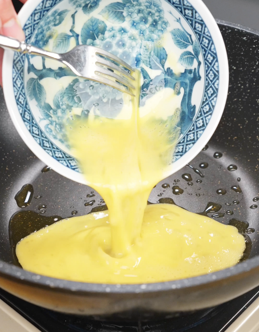 Beaten eggs being poured into a hot pan to make soft scrambled eggs for this quick and flavorful Chili Oil Butter Fried Rice Recipe.