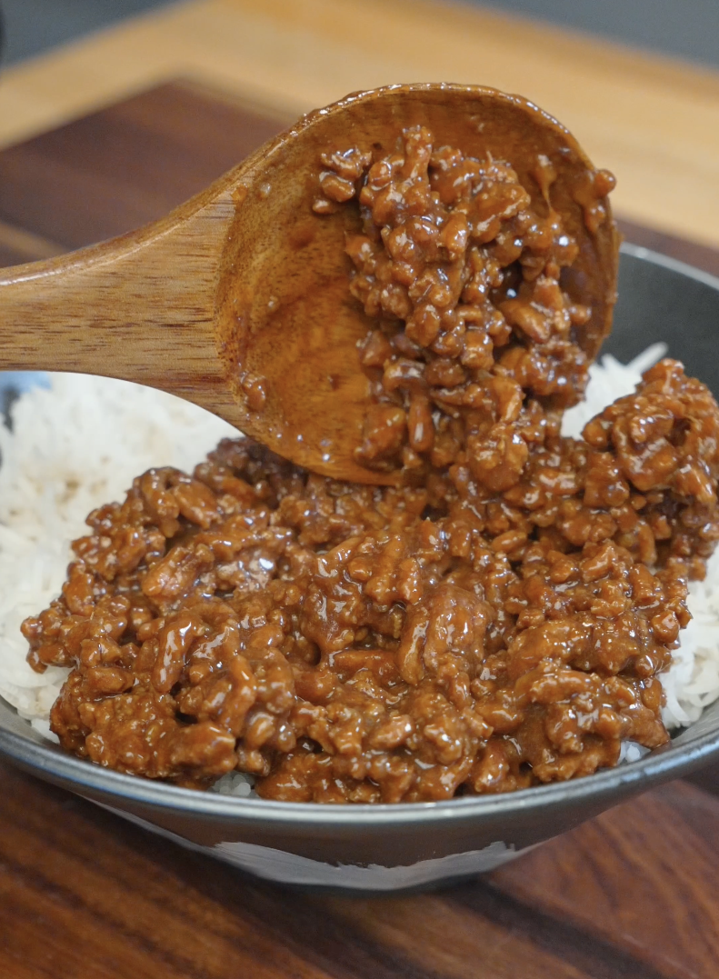 Wooden spoon serving glossy soy-glazed ground beef over steamed rice in the Japanese Ground Beef Egg Bowl Recipe with a rich savory sauce coating every bite.