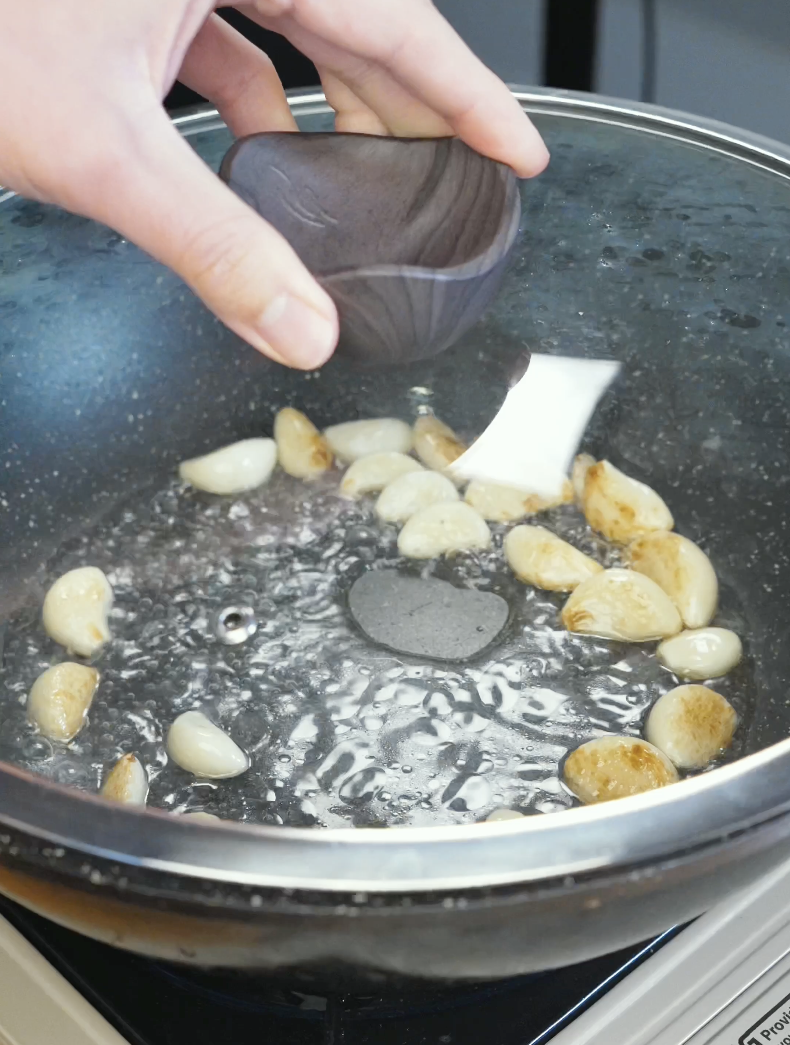 Water being added into a pan of garlic cloves before covering to soften the garlic for the Whole Garlic Chicken Stir Fry Recipe.