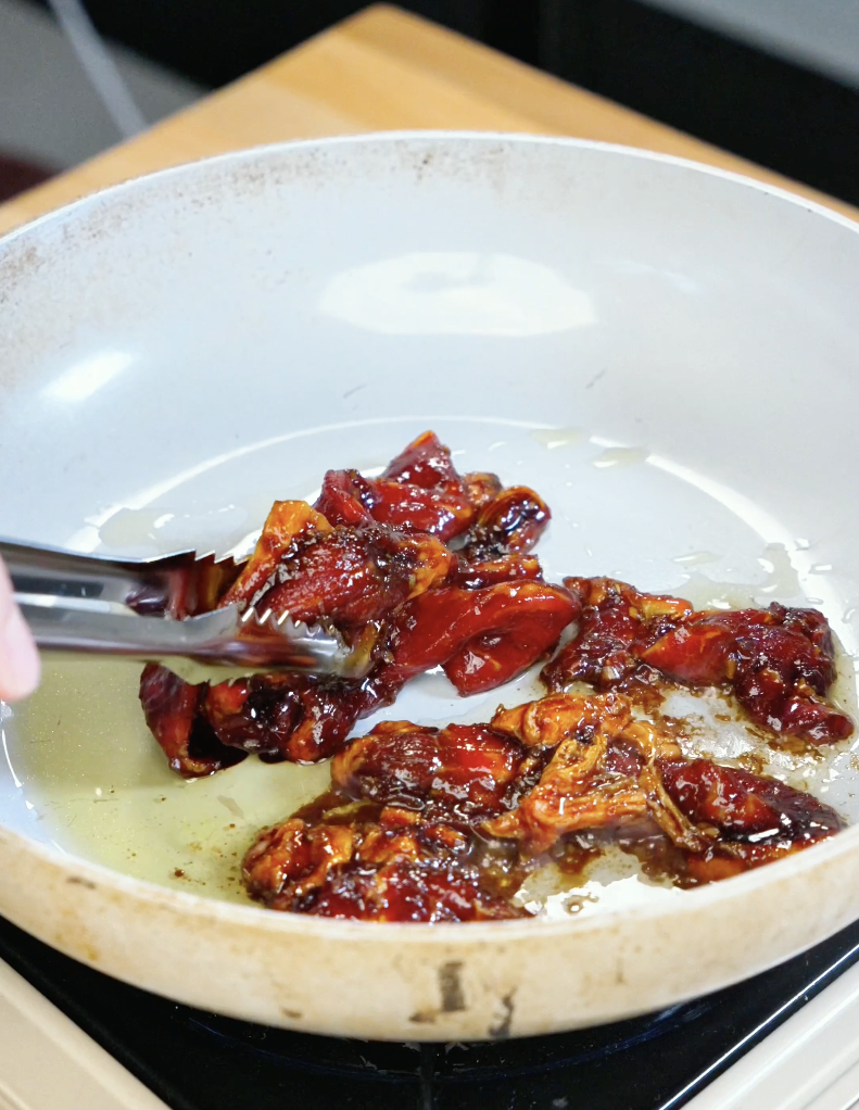 Tongs tossing thinly sliced beef coated in a sticky lemongrass garlic marinade while cooking in a skillet for this savory homemade Lemongrass Beef Recipe.