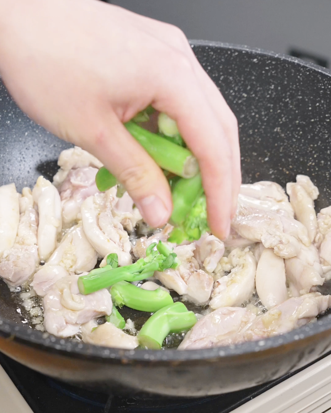 Chinese broccoli stems being added to a pan with chicken and garlic while making this Pad See Ew Recipe.