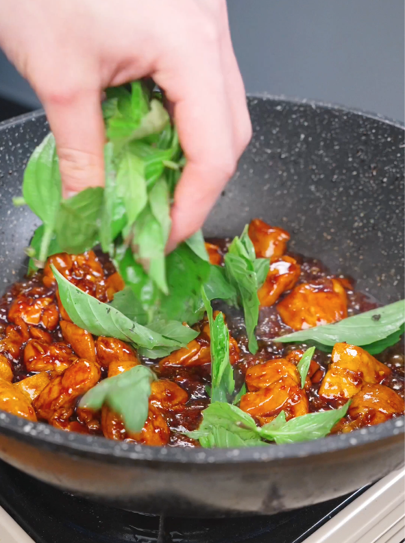 Fresh Thai basil being added to the pan to finish this Three Cup Chicken Recipe.
