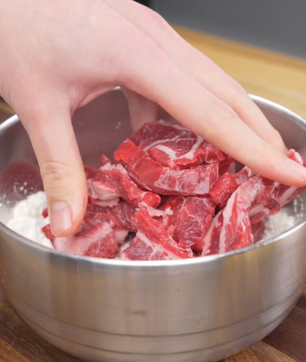 Thinly sliced flank steak being tossed in a mixture of flour, cornstarch, and salt to create the crispy coating for this Crispy Chili Beef Recipe.