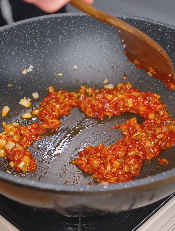 Gochujang cooking with sautéed onion and garlic in a pan to deepen the flavor for this Gochujang Vodka Pasta Recipe.
