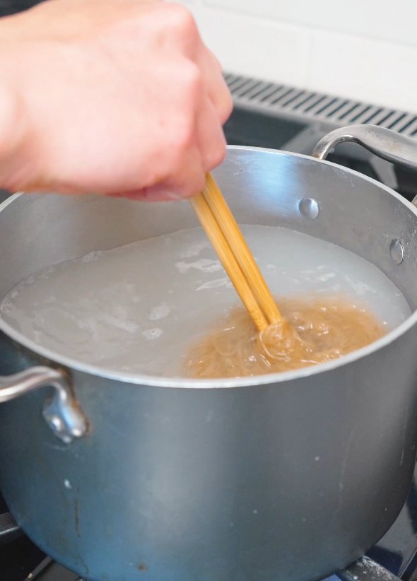 Thin noodles boiling in a pot of water before being chilled for this Spicy Cold Noodles Recipe.