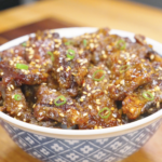 Bowl of Crispy Honey Garlic Beef Recipe coated in a glossy honey garlic sauce and topped with sesame seeds and sliced scallions. This easy air fryer beef recipe delivers crispy, tender bites with sweet and savory flavor.