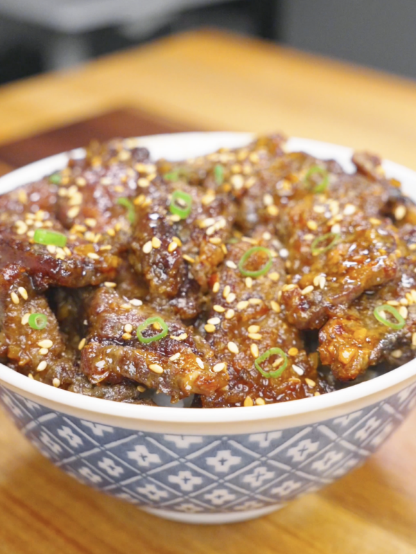 Bowl of Crispy Honey Garlic Beef Recipe coated in a glossy honey garlic sauce and topped with sesame seeds and sliced scallions. This easy air fryer beef recipe delivers crispy, tender bites with sweet and savory flavor.