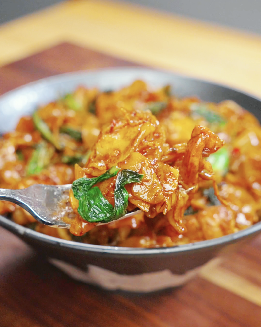Forkful of Drunken Noodles Recipe featuring chewy rice noodles, chicken, and Chinese broccoli coated in a savory sauce. The noodles are glossy and packed with classic Pad Kee Mao flavor.