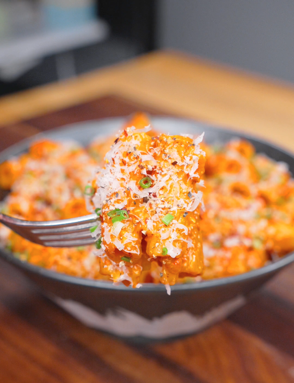 A fork lifting a bite of creamy Gochujang Vodka Pasta Recipe coated in a spicy vodka cream sauce with parmesan and chives.