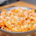 A bowl of creamy Gochujang Vodka Pasta Recipe topped with freshly grated parmesan, chopped chives, black pepper, and red pepper flakes.