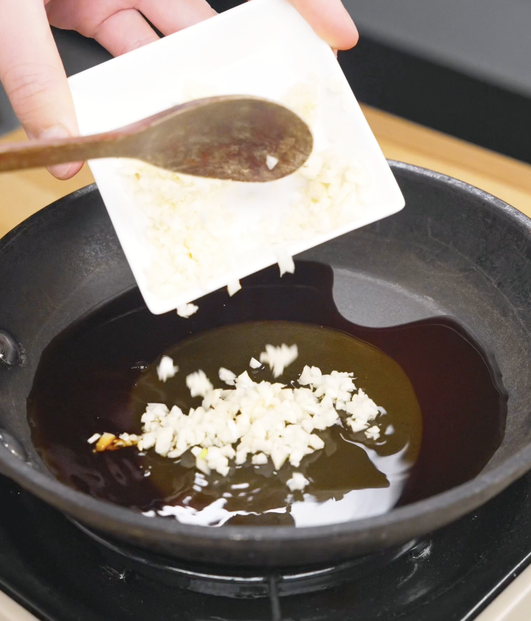 Minced garlic being added to a pan with honey, soy sauce, and rice vinegar while making the sauce for a Crispy Honey Garlic Beef Recipe. The garlic adds rich savory flavor to the glaze.