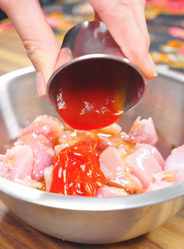 Ketchup being poured over chicken thighs with honey, soy sauce, rice vinegar, and garlic to marinate for this Sweet Honey Chicken Recipe.