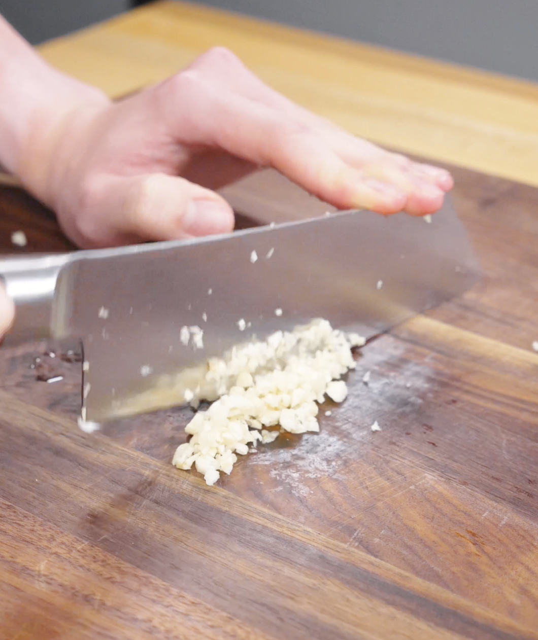 Fresh garlic being finely minced on a cutting board to build the flavor base for this Pad See Ew Recipe.