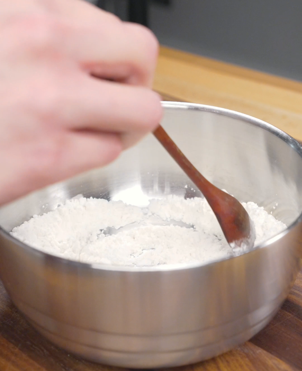 Flour, cornstarch, and salt being mixed together in a bowl for a Crispy Honey Garlic Beef Recipe. This simple coating helps create a crispy exterior on the air-fried beef.