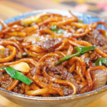 Mongolian Beef Noodles Recipe served in a bowl with tender beef, chewy noodles, onions, and scallions coated in a savory sauce.