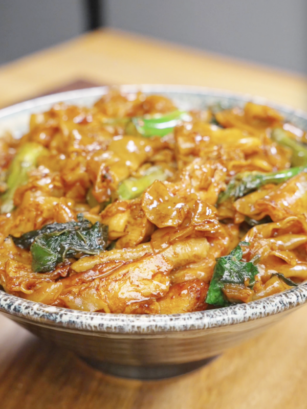 A bowl of Pad See Ew Recipe made with wide rice noodles, chicken, Chinese broccoli, egg, and a savory soy sauce glaze.