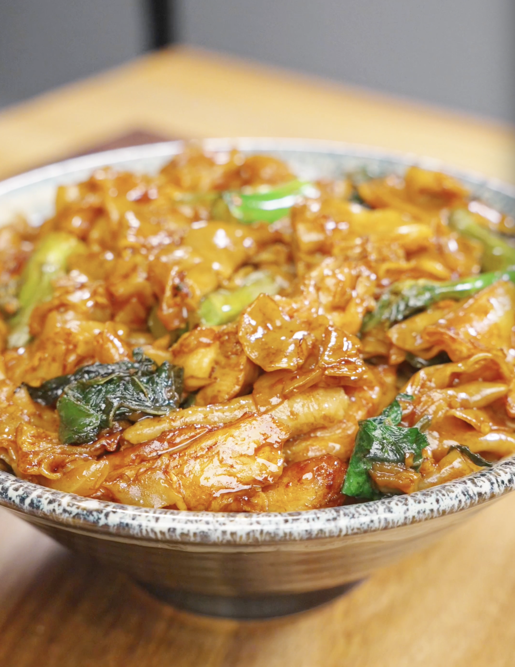 A bowl of Pad See Ew Recipe made with wide rice noodles, chicken, Chinese broccoli, egg, and a savory soy sauce glaze.