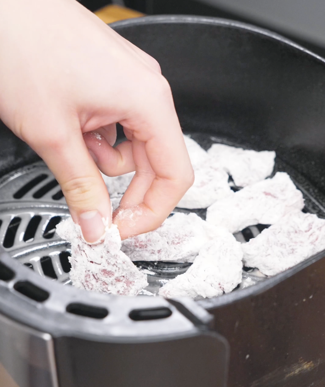 Coated beef being placed in air fryer to be crisped up for this Crispy Honey Garlic Beef Recipe.
