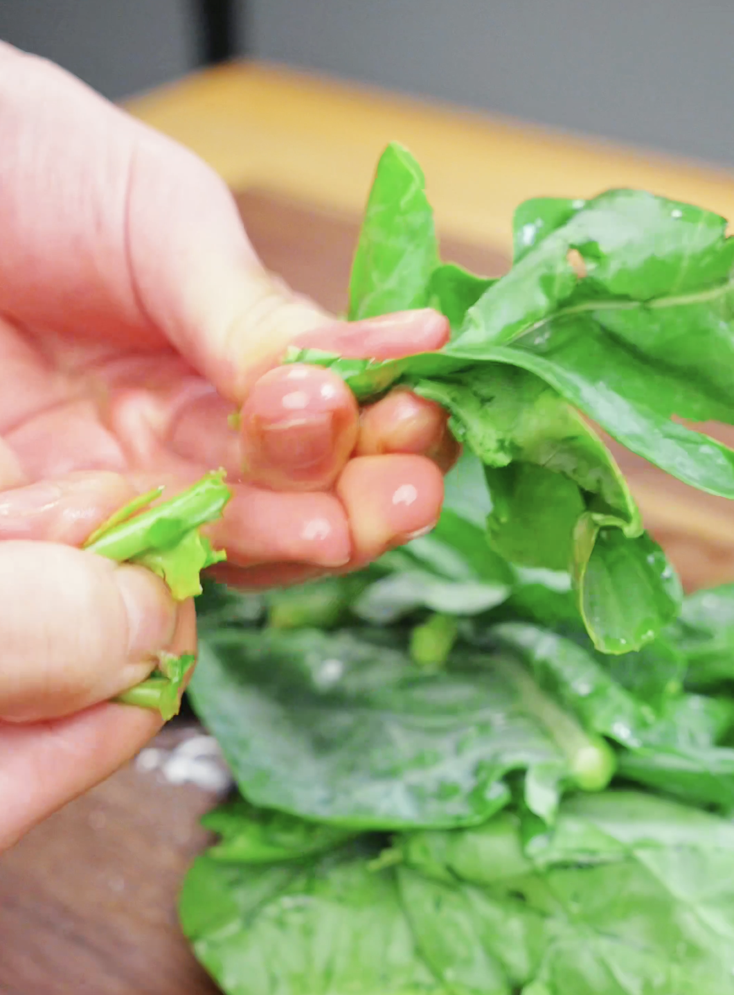 Chinese broccoli leaves being separated from the stems for a Drunken Noodles Recipe. Preparing the greens this way helps the stems and leaves cook evenly in the stir fry.