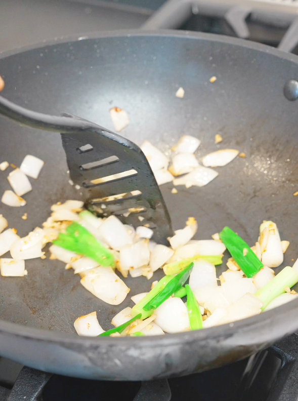 Onion, garlic, and scallion whites cooking in a pan for the Mongolian Beef Noodles Recipe.