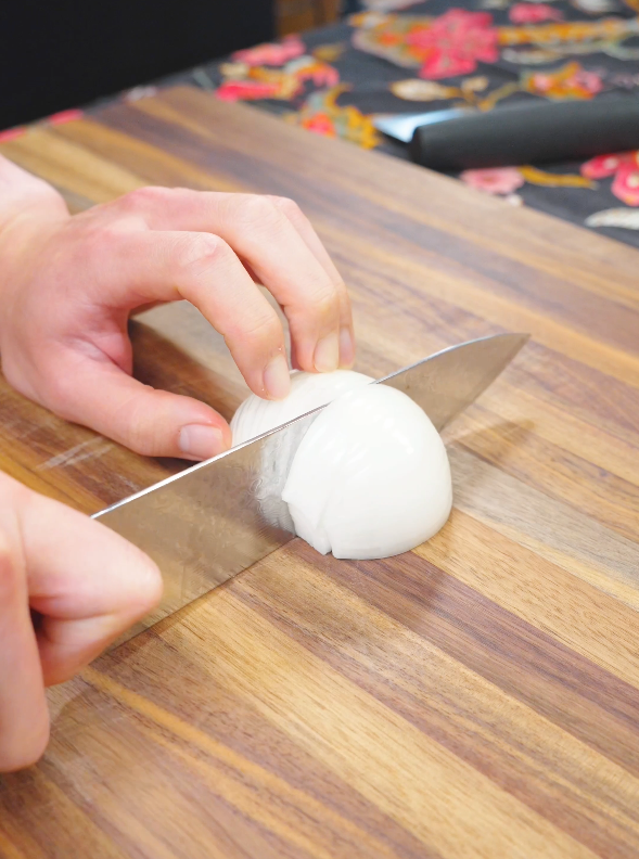 A small onion being sliced on a cutting board for the Mongolian Beef Noodles Recipe.