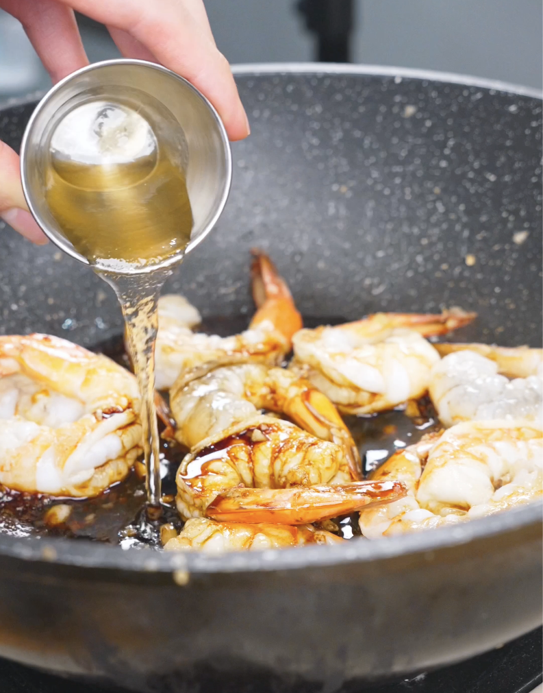 Honey being poured over the shrimp and soy sauce in the pan for Honey Garlic Shrimp Recipe.