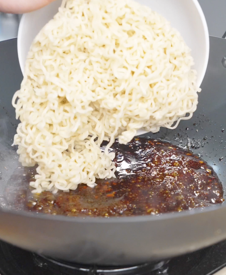 Cooked ramen noodles being added into the pan of hoisin sauce for Hoisin Garlic Noodles Recipe.