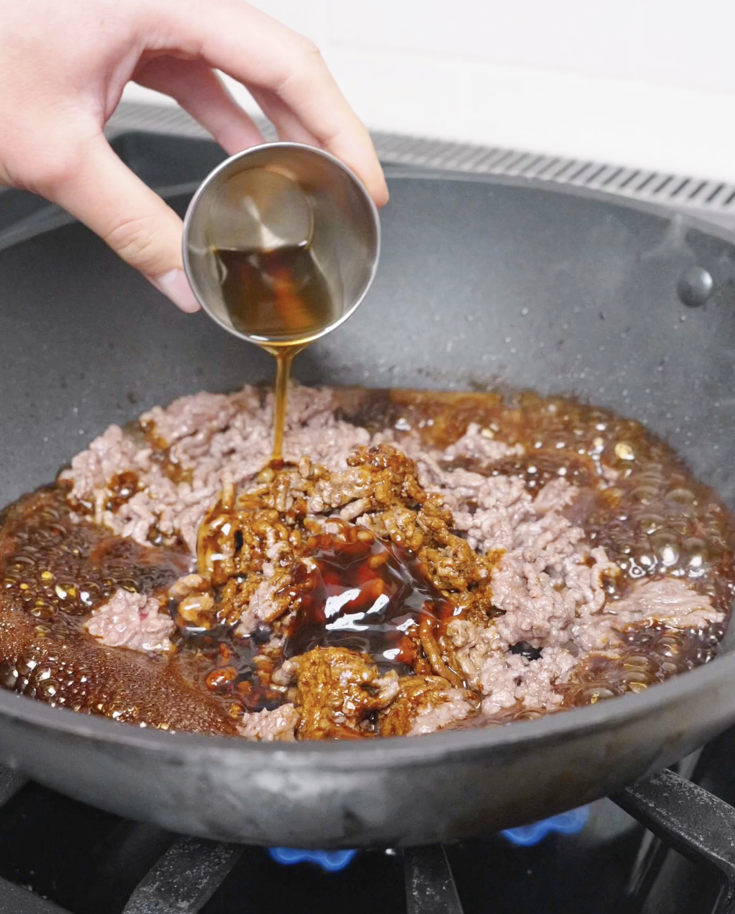 Dark soy sauce, light soy sauce, oyster sauce, sesame oil, and brown sugar being added to Sticky Sweet Ground Beef Recipe.