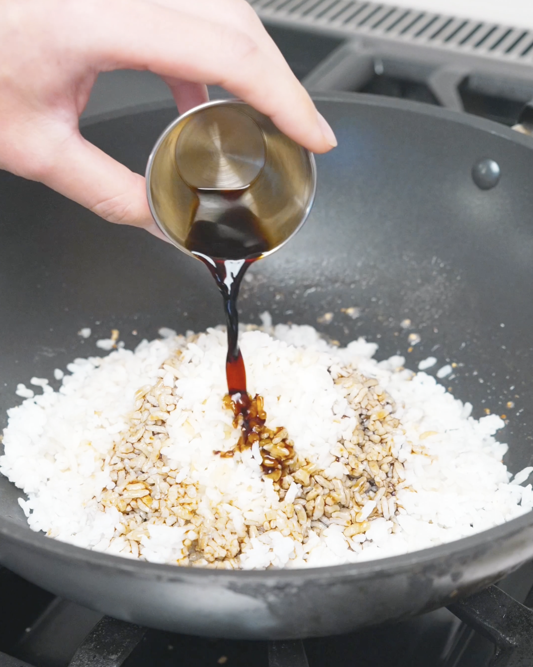 Soy sauce being poured over the rice while making Garlic Butter Fried Rice Recipe.