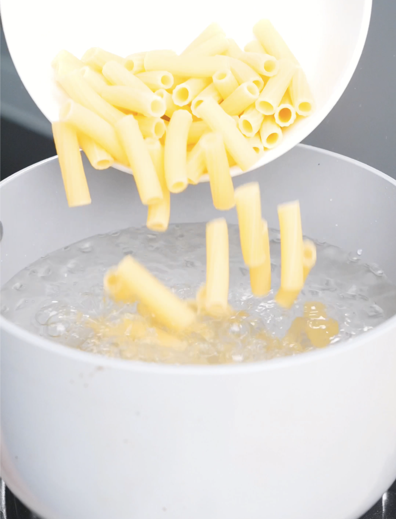 Rigatoni being poured into a pot of boiling water for Creamy Garlic Chicken Pasta Recipe.