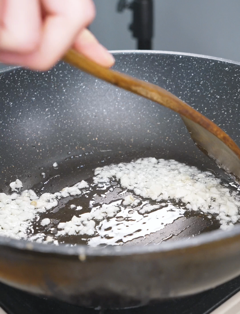 Minced garlic sizzling in oil in a pan while starting Honey Garlic Shrimp Recipe.